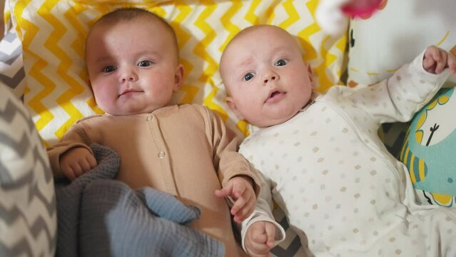 two twins lie in a bed. happy family kid dream concept. cute twins lie in bed in the bedroom in the evening smile look at the toy. newborn boy and lifestyle girl brother and sister