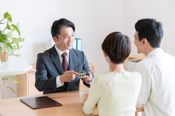 夫婦に不動産の営業をするビジネスマン