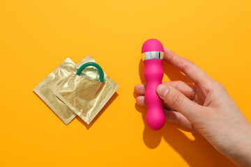 Condoms and vibrator on a yellow background