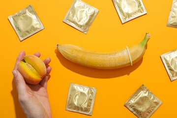 A condom on a banana with a peach on a yellow background