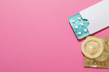 Condoms and birth control pills on a pink background, place for text