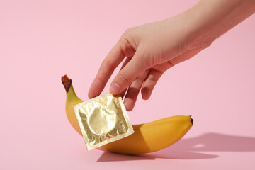 Condom and banana on a pink background