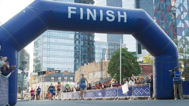 Slow Motion of a Diverse Group of People Crossing the Finish Line in a City Marathon During the Day. Resilient Winning Runners Celebrating While Their Family and Friends Cheer for Them
