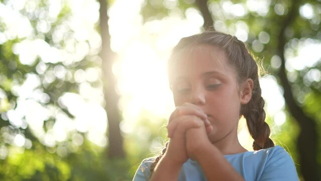 child pray. young gratitude a god religion concept. little girl in nature outdoors praying dreams of happiness to god. praise worship freedom concept. kid praying in lifestyle the forest
