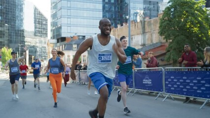 Slow Motion Portrait of Smiling Young Black Man Running in a City Marathon, Waving at the Supportive Audience. Friendly Happy Male Runner Celebrating Crossing the Finish Line in a Race