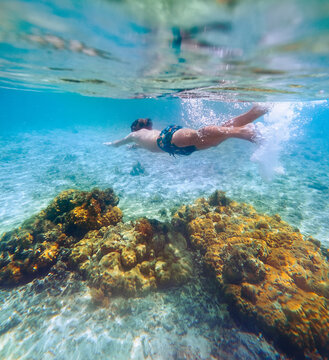 Diving teenage boy snorkeling over the coral reefs underwater photo in the clean turquoise lagoon on Le Morne beach. Mauritius island. Exotic traveling and underwater eco concept.