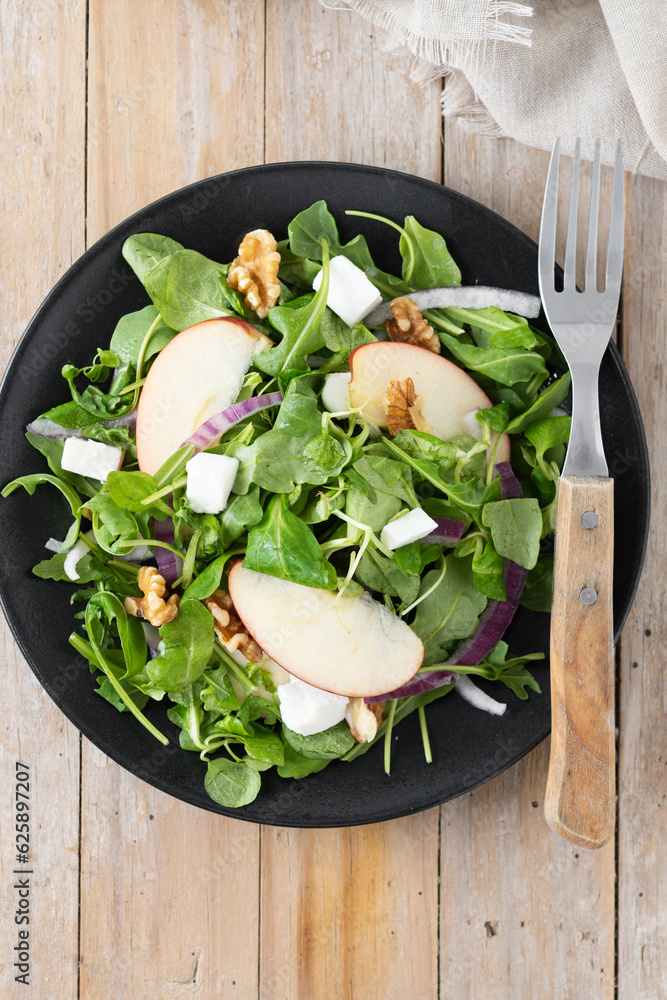 Wall mural Autumn salad with apples and walnuts on wooden table. Top view