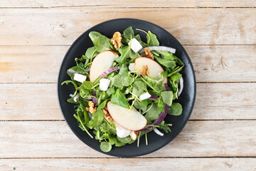 Autumn salad with apples and walnuts on wooden table. Top view