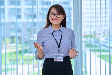 Middle aged woman with educational center id card, in office near window
