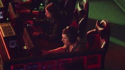 From above slowmo of team of young professional gamers rejoicing when winning in esports contest at night computer club