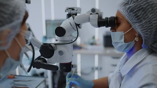 Microsurgery And Cosmetic Dentistry, Female Doctor Looking In Operating Microscope, Dental Clinic