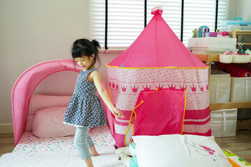 Naklejka premium Little girl be cheeky ,look so funny and playful in her play room at home.Home child room decoration design.