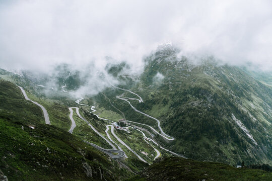 A Winding Mountain Road In Switzerland On A Misty Morning 
