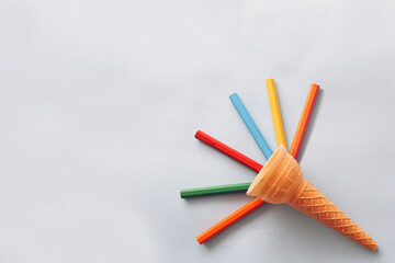Creative colorful wooden pencils in epmty ice cream cornet on blue background with copy space. Flat...