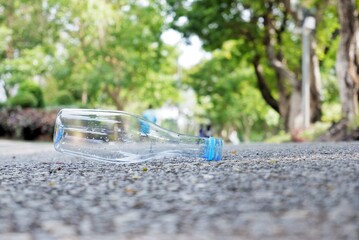 An empty of drinking plastic bottle littering on the ground floor in plubic park road with blurred...