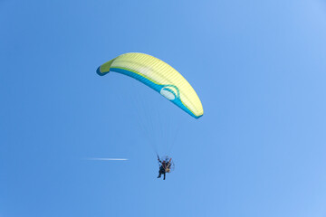 Paragliding, flying in the sky and high passenger airliner jet contrail.