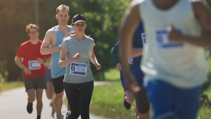 Slow Motion Portrait of a Woman Running and Participating in a Marathon in a Park. Strong Athletic Female Jogger Racing Other Runners with Determination for the First Place in the Finish Line