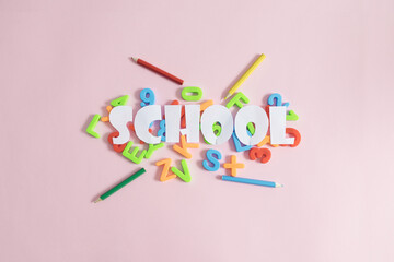 Creative layout with colorful school elements, letters, numbers, pencils, and Word SCHOOL on pink pastel background. School concept. Flat lay.