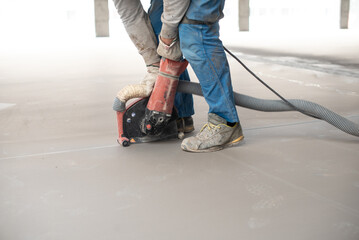 Crop anonymous man leveling floor with machine during construction