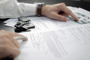 Man signing car insurance document or lease paper. Writing signature on contract or agreement. Buying or selling new or used vehicle. Car keys on wooden table. Warranty or guarantee. - 625916291