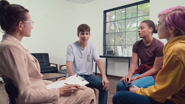 Wide shot of multi-ethnic teenagers at group circle session with psychologist