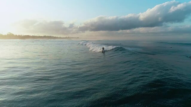 Surfer athletic man riding wave surfboard tropical resort extreme sport leisure activity aerial panorama view. Athlete on a wave board rides the big ocean waves of a living reef in the Indian Ocean