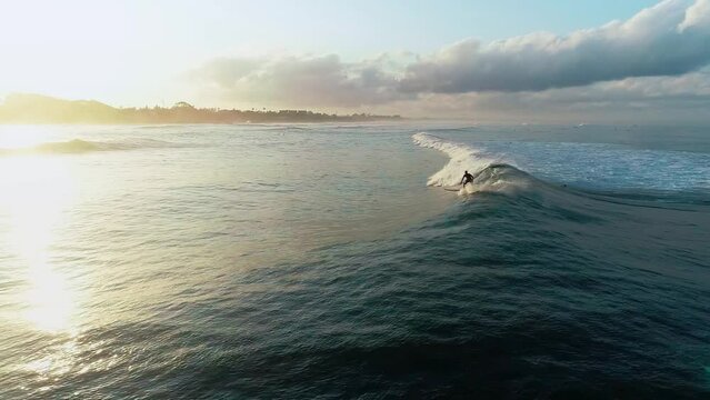 Surfer athletic man riding wave surfboard tropical resort extreme sport leisure activity aerial panorama view. Athlete on a wave board rides the big ocean waves of a living reef in the Indian Ocean
