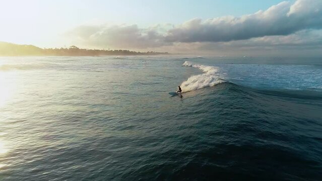 Surfer athletic man riding wave surfboard tropical resort extreme sport leisure activity aerial panorama view. Athlete on a wave board rides the big ocean waves of a living reef in the Indian Ocean