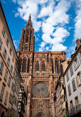 Bell tower and west front facade of Strasbourg Cathedral (Cathedral of Our Lady) in Alsace, France. Church built with reddish-brown sandstone with rose window and details. Major monument and sight