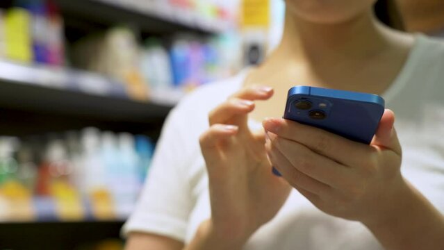 Woman shopping in a supermarket looking at the screen of the phone her shopping list