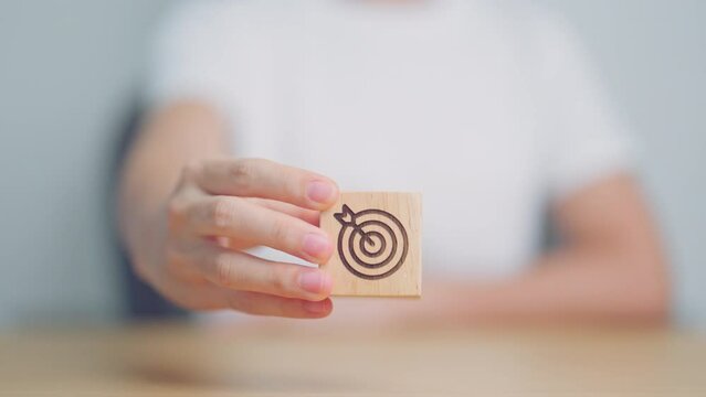 hand hold dartboard block with business goal, strategy, target, mission, action, objective, aim and success concept