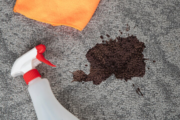  Dark stain, dirty spot on a carpeted floor, cleaning cloth, stain remover spray.