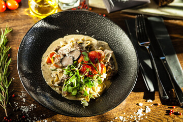 Black Angus beef tagliatelle pasta with fresh black truffles and parmegano. Delicious healthy traditional food closeup served for lunch in modern gourmet cuisine restaurant