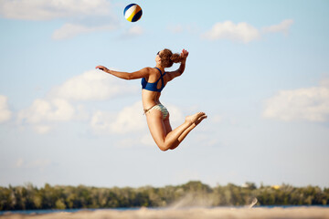 Young sportive, athletic woman in swimsuit playing beach volleyball outdoors on sand near river. Fresh air and training. Concept of sport, active and healthy lifestyle, hobby, summertime, ad