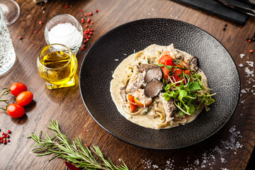 Black Angus beef tagliatelle pasta with fresh black truffles and parmegano. Delicious healthy traditional food closeup served for lunch in modern gourmet cuisine restaurant - obrazy, fototapety, plakaty