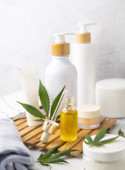 Obraz na płótnie Canvas Dropper bottle with CBD oil near green cannabis leaves near bottles and towel close up