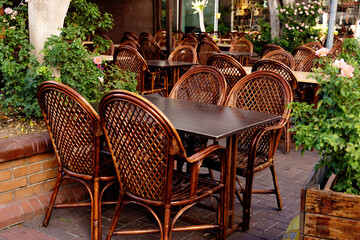 Fototapeta na wymiar Wooden wicker chairs in a street restaurant. Outdoor cafe in the city. Urban lifestyle.