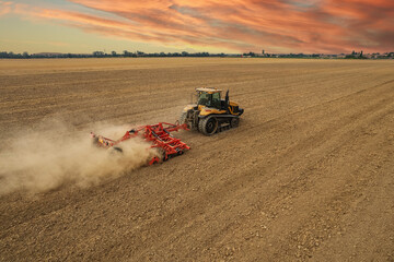 Crawler tractor harrowing and leveling soil for next seeding in rural plain fields