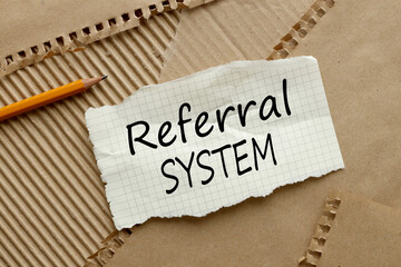 top view of torn notepad paper. words REFERRAL SYSTEM