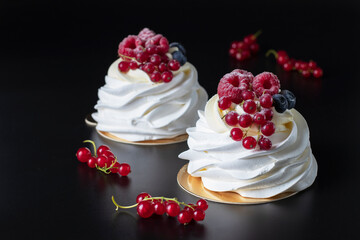 Mini Pavlova cake with raspberry, blueberry and red currant on black background, Closeup