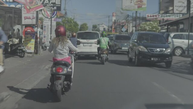 A shot of a Woman Driving A Bike In Traffic, filmed from the behind
