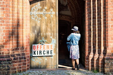 malchow, deutschland - 01.09.2021 - frau betritt kirchenportal mit schild offene kirche