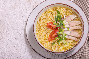 Spicy noodles with beef broth. Hot dish, cutlery, hard light, dark shadow. Stone concrete background