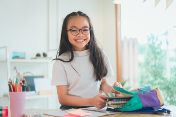Pupil child put books and notes into backpack. School supplies.Back to school concept. Kid prepare for studies. Portrait cute little girl packing backpack .