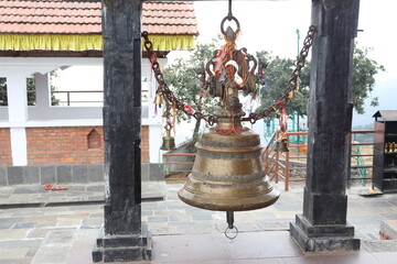 Close up view of a temple bell made up of bronze material, hanged in between two pillars