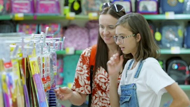 Mom and daughter in the supermarket choose stationery before the new school year