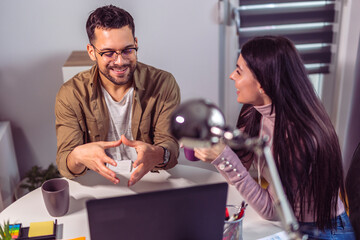 Young couple of freelancers work from home. A guy and a girl in casual clothes work in the living room.