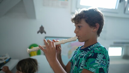 Kid playing flute young boy plays musical instrument © Marco