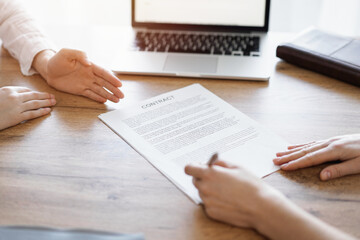 Business people signing contract papers while sitting at the wooden table in office, closeup. Partners or lawyers working together at meeting. Teamwork, partnership, success concept