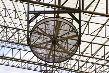 Mist fan big size, water mister fan blows. Able to cool well. Installed under strong steel beam roof. Translucent metal roof in a park, with sunlight shining inside. from natural light. 